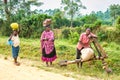 Woman and two boys transport heavy goods on their heads and on a wooden scooter to the street market in Uganda.