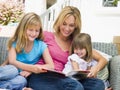 Woman and two young girls sitting on patio reading Royalty Free Stock Photo