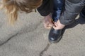 A woman is tying a lace on her boot. Sitting on a knee, hands tie a knot on the untied cord while walking Royalty Free Stock Photo