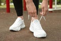 Woman tying laces of stylish sneakers outdoors Royalty Free Stock Photo