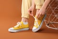 Woman tying shoelace of classic old school sneaker on brown background, closeup Royalty Free Stock Photo