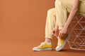 Woman tying shoelace of classic old school sneaker on brown background, closeup. Space for text Royalty Free Stock Photo