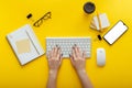 Woman typing on computer keyboard at workplace on color yellow background. Office desktop workspace with female hands Royalty Free Stock Photo