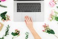 Woman typing on laptop. Beautiful workspace with female hands, laptop, notebook and pink flowers on white background. Top view. Fl Royalty Free Stock Photo