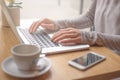 Woman typing on laptop computer and using smart phone