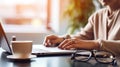 Woman typing on a laptop in front of a cup of coffee