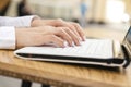 Woman typing on a laptop keyboard in a warm sunny day outdoors, sitting at the cafe table. Space for text Royalty Free Stock Photo