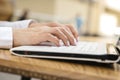 Woman typing on a laptop keyboard in a warm sunny day outdoors, sitting at the cafe table. Space for text Royalty Free Stock Photo