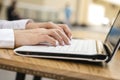 Woman typing on a laptop keyboard in a warm sunny day outdoors, sitting at the cafe table. Space for text Royalty Free Stock Photo