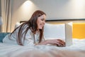 Woman typing on laptop lying on bed in bedroom, having online shopping or smiling and enjoying freelance working at home Royalty Free Stock Photo