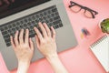 Woman typing on laptop in pink pastel colourful office with accessories Royalty Free Stock Photo