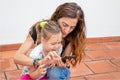 Woman typing on mobile and little girl watching smiling