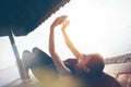 Woman typing on mobile phone near ocean, sun shelter on the beach Royalty Free Stock Photo