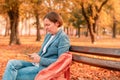 Woman typing text message on mobile phone on park bench Royalty Free Stock Photo