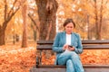 Woman typing text message on mobile phone on park bench Royalty Free Stock Photo