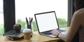 A woman is typing on a white blank screen computer laptop at the wooden working desk Royalty Free Stock Photo