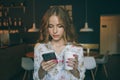 Woman typing write a message on a smartphone in a modern cafe. image of a young beautiful girl with coffee or cappuccino Royalty Free Stock Photo