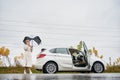 Woman with umbrella standing near car and speaking on phone. Royalty Free Stock Photo