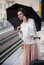 Woman with umbrella at train station holding phone Royalty Free Stock Photo