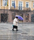 Woman with umbrella walking down the street on rainy day. Intentional motion blur