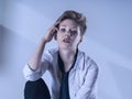 Woman in unbuttoned white shirt and tie sitting on a chair