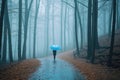 Woman under blue umbrella walks in the park on a foggy day. Generative AI Royalty Free Stock Photo