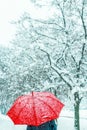 Woman under red umbrella walking in winter snow