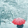 Woman under red umbrella walking in winter snow