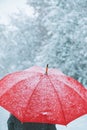 Woman under red umbrella walking in winter snow