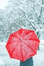 Woman under red umbrella walking in winter snow