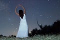 Woman under starry night in white long dress ballet pose raising arms Woman under night sky Royalty Free Stock Photo