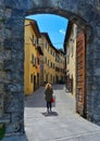 Woman under stone gate in narrow street in old historic alley in the medieval City of Cortona near city of Arezzo in T