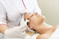 Woman undergoes the procedure of medical micro needle therapy with a modern medical instrument derma roller.