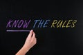 Woman underlining phrase Know the rules on chalkboard, closeup