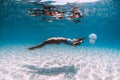 Woman underwater over sandy sea with jellyfish. Freediving in blue ocean