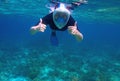 Woman underwater shows thumb up. Snorkel in coral reef of tropical sea. Young girl in full-face snorkeling mask. Royalty Free Stock Photo