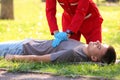 Woman in uniform performing CPR on unconscious man outdoors.