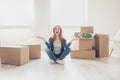 Woman unlimitedly happy because of moving new house of her dream, sitting on the floor with lots of cardboard boxes