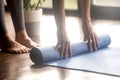Woman unrolling blue yoga mat, legs close up Royalty Free Stock Photo