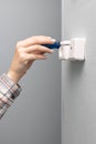 a woman unscrews with a screwdriver repairing a television wall socket