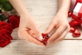 Woman unwrapping heart shaped chocolate candy at white wooden table, closeup