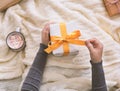 Woman unwrapping small Christmas present and drinking hot chocolate