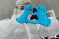 Woman up close in blue medical gloves shows signs of heart