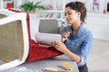 woman upholstering chair looking at notebook for inspiration