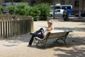 Woman use of cellphone while seating in park in old town Royalty Free Stock Photo