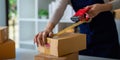 Woman use scotch tape to attach parcel box to prepare goods for the process of packaging, shipping, online sale internet