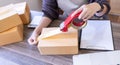 Woman use scotch tape to attach parcel boxes to prepare goods for the process of packaging, shipping, online sale