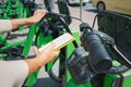 Woman uses app in her smartphone to rent a shared electric bike for a trip around the city. Solving the problem of transport in