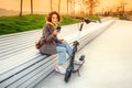 Woman uses app on her smartphone to unlock a shared electric scooter on a city street. New eco-friendly transport