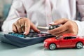 woman uses a calculator while signing a contract document for car insurance. Royalty Free Stock Photo